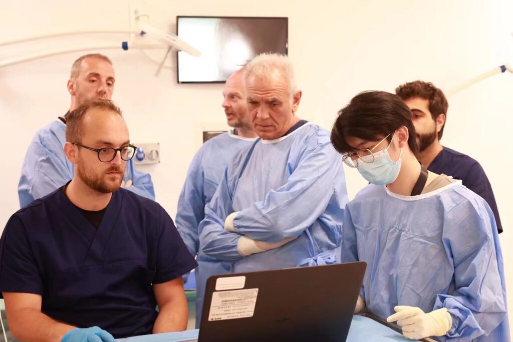 An international group of focused veterinarians, led by a senior expert, intently studying a case on a laptop in a modern training facility.
